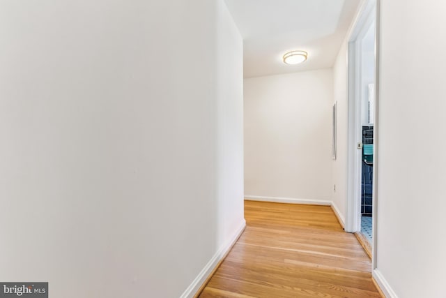 hall with baseboards and light wood finished floors