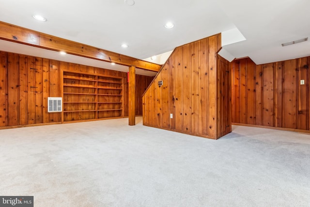 finished basement with wood walls, carpet, built in features, and visible vents