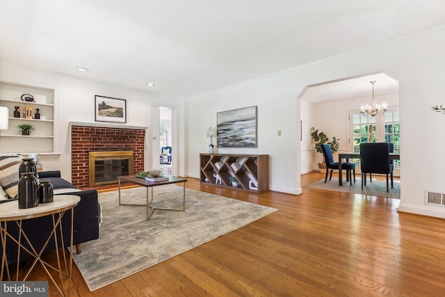 living room with baseboards, an inviting chandelier, wood finished floors, and visible vents