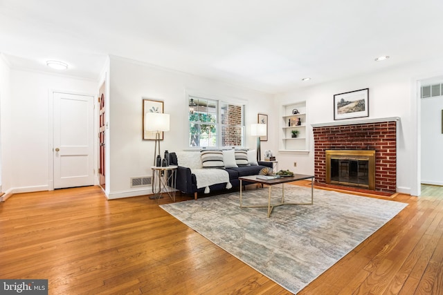 living room featuring light wood-style floors, built in features, baseboards, and visible vents
