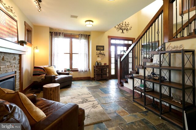 441 Millgate Rd, Bellefonte, PA 16823 - living room with a stone fireplace, stone tile flooring, stairway, and baseboards