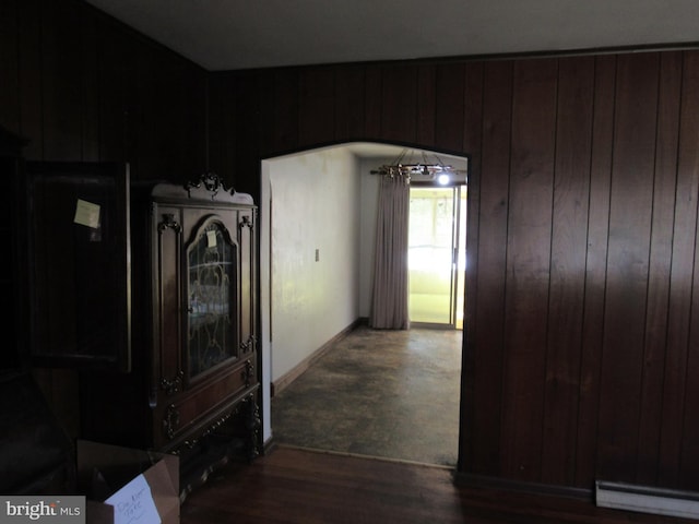 corridor with baseboards, wood walls, and wood finished floors