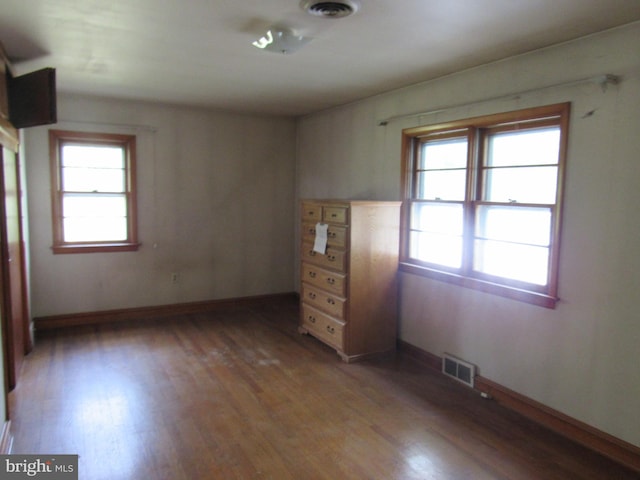 spare room with a wealth of natural light, wood finished floors, and visible vents