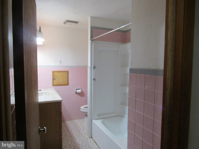 full bathroom featuring tile patterned flooring, vanity, wainscoting, toilet, and tile walls
