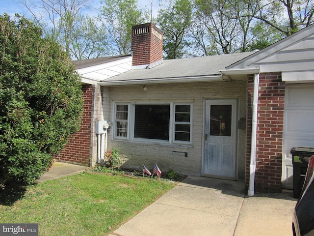 property entrance with brick siding, a yard, and a chimney