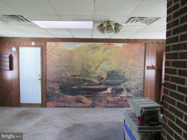 interior space featuring visible vents, carpet, a drop ceiling, and wooden walls