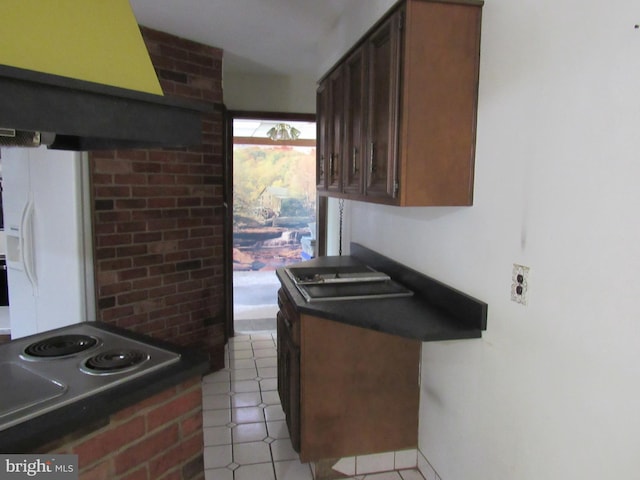 kitchen featuring dark countertops, light tile patterned floors, dark brown cabinets, and white fridge with ice dispenser