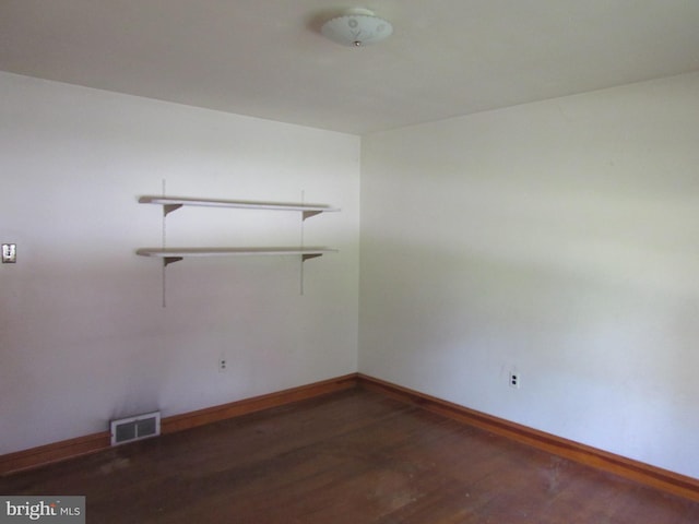 empty room with baseboards, visible vents, and wood finished floors