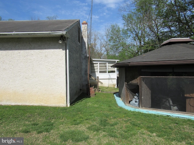 view of home's exterior with a lawn, stucco siding, and a chimney