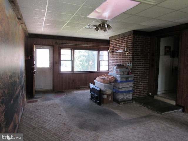 interior space featuring visible vents, carpet, wood walls, and a paneled ceiling