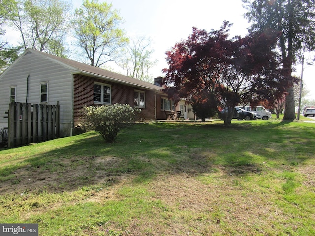 rear view of property with brick siding, a yard, and a chimney