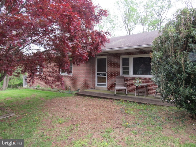 rear view of house featuring a lawn, brick siding, and a shingled roof