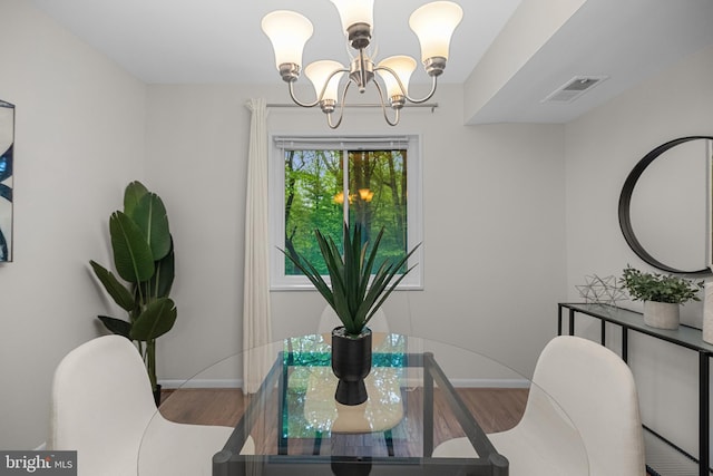 dining area with wood finished floors, a chandelier, visible vents, and baseboards