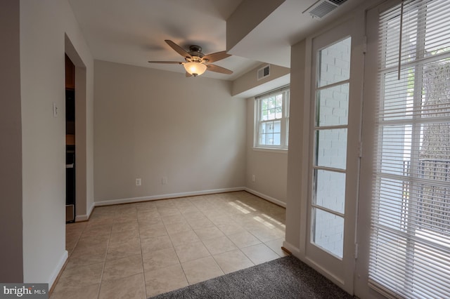 spare room with light tile patterned floors, visible vents, ceiling fan, and baseboards
