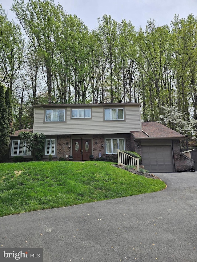 view of front of home featuring a front lawn, a garage, aphalt driveway, and brick siding