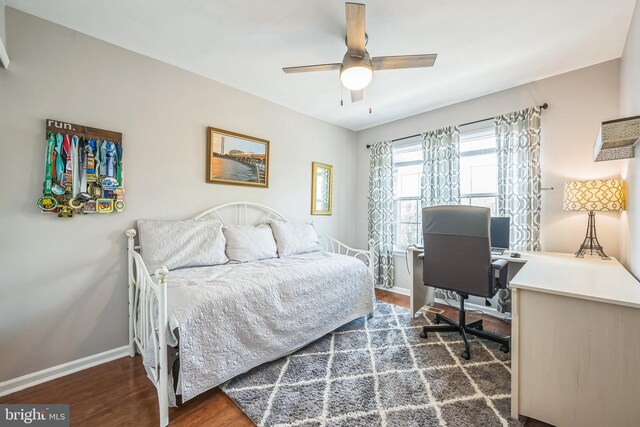 bedroom with a ceiling fan, baseboards, and dark wood-type flooring