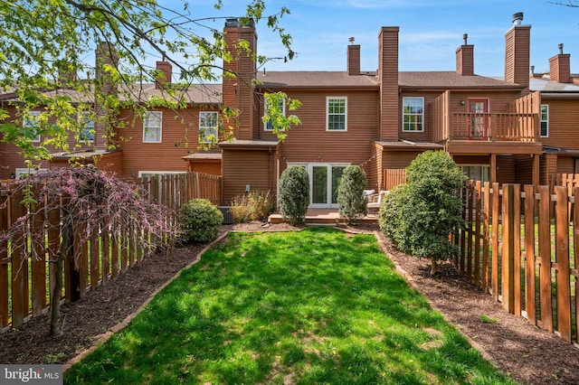 back of property featuring a chimney, a fenced backyard, and a yard
