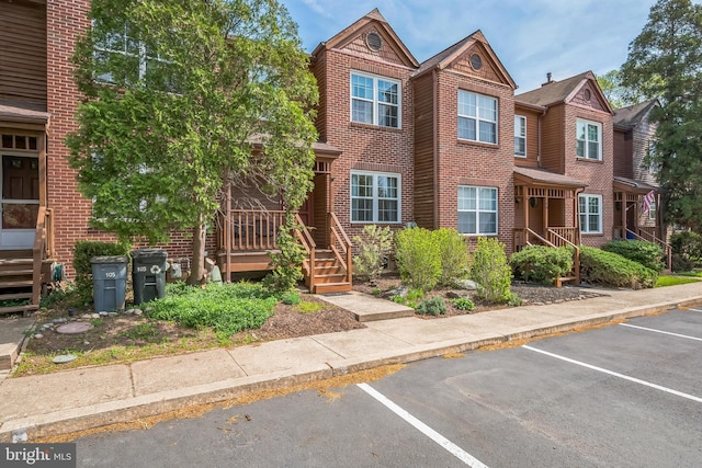 view of property featuring stairway, uncovered parking, and brick siding