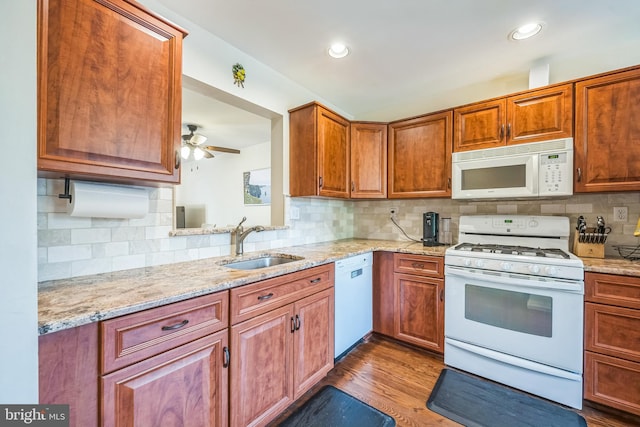 kitchen featuring light stone countertops, a sink, tasteful backsplash, and white appliances