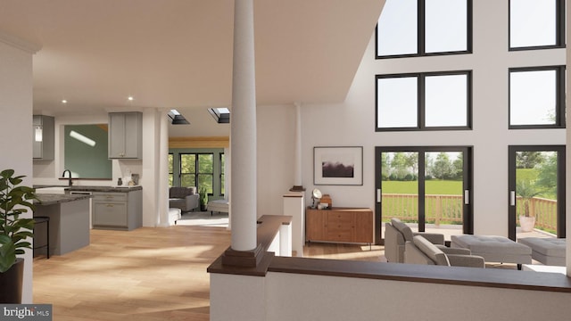 living area with recessed lighting, light wood finished floors, and a towering ceiling