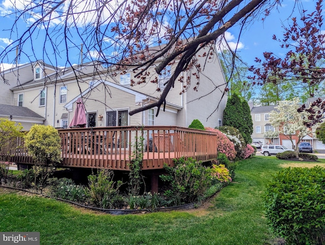 rear view of property featuring a deck and a lawn