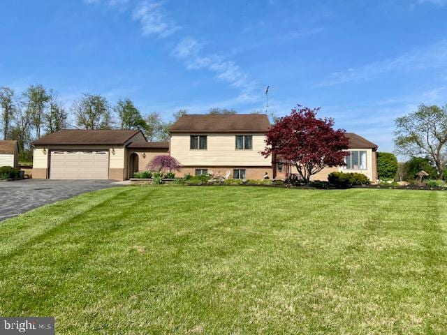 tri-level home featuring a garage, driveway, and a front yard