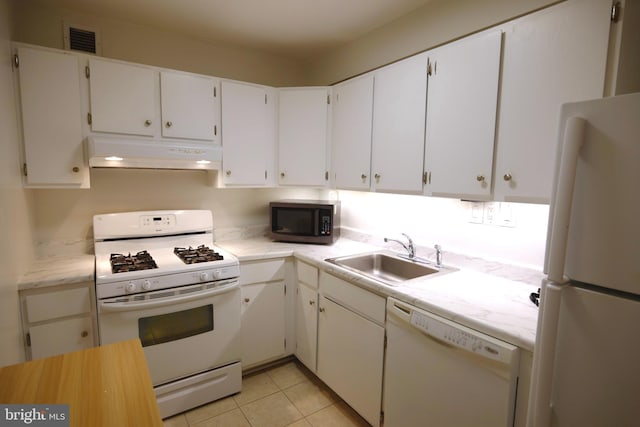 kitchen featuring white appliances, under cabinet range hood, light countertops, a sink, and visible vents