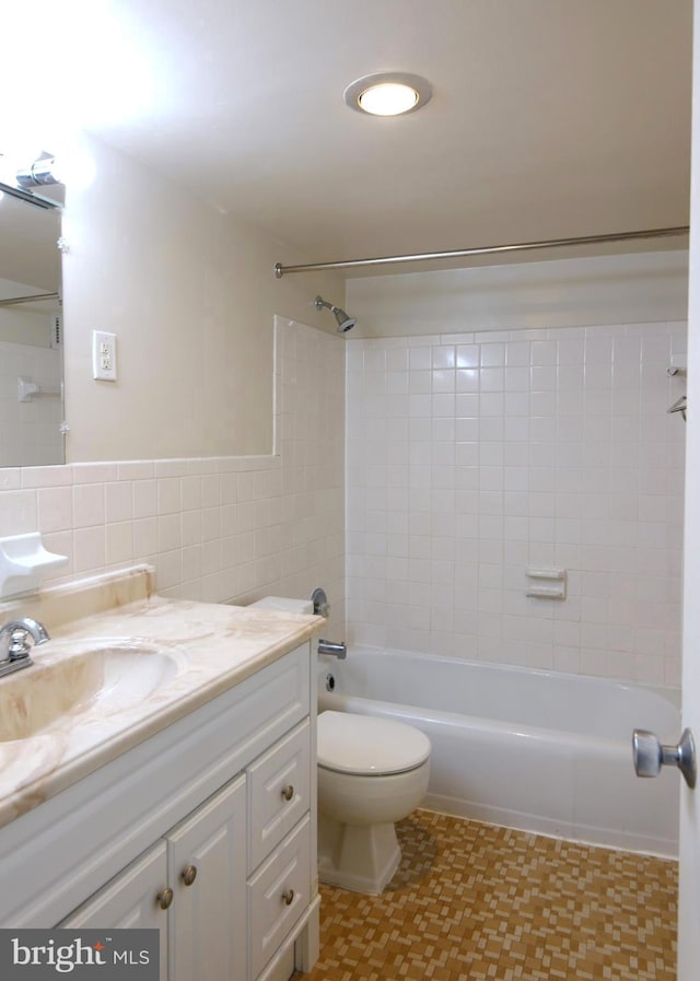 full bathroom with tile walls, washtub / shower combination, vanity, tile patterned floors, and toilet