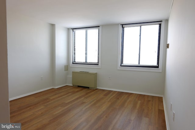 spare room with baseboards and wood finished floors