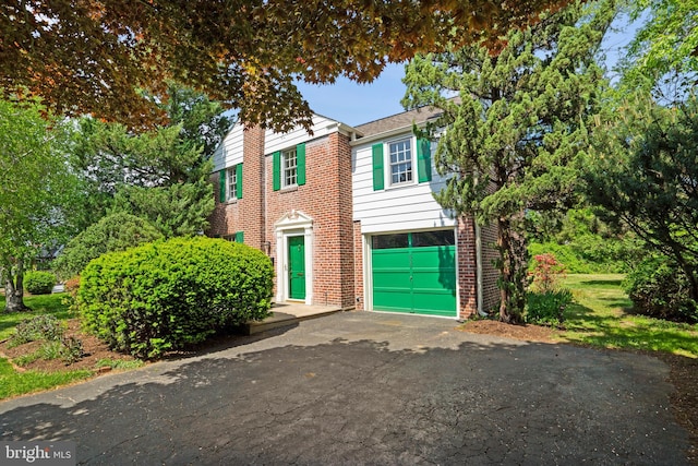 view of front facade featuring brick siding, an attached garage, and driveway