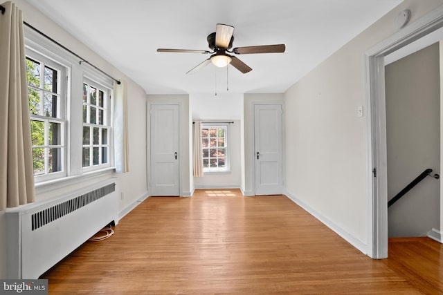 empty room with radiator heating unit, plenty of natural light, and light wood finished floors