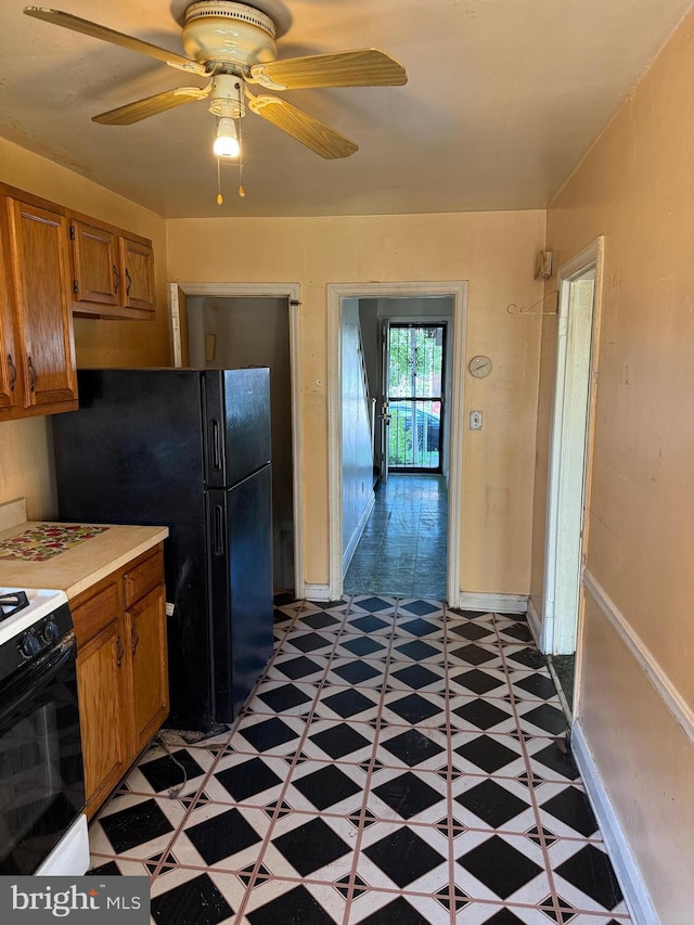 4333 Pimlico Rd, Baltimore, MD 21215 - kitchen featuring brown cabinetry, light countertops, freestanding refrigerator, light floors, and gas range oven
