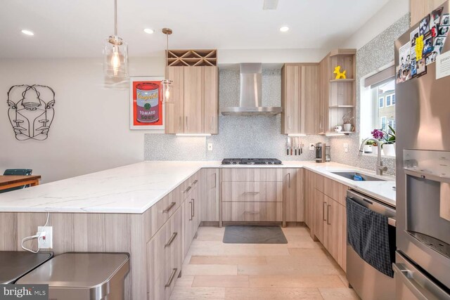 kitchen with stainless steel appliances, light brown cabinets, a peninsula, and wall chimney exhaust hood