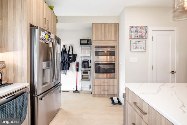 kitchen with light stone counters, light brown cabinets, stainless steel appliances, and modern cabinets
