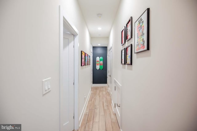 corridor featuring baseboards, recessed lighting, and light wood finished floors