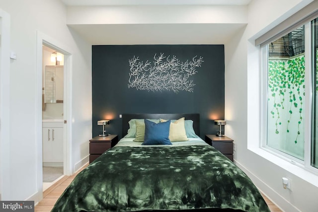 bedroom with baseboards, wood finished floors, and ensuite bath