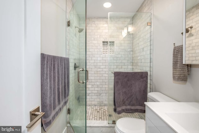 bathroom featuring vanity, toilet, and a stall shower