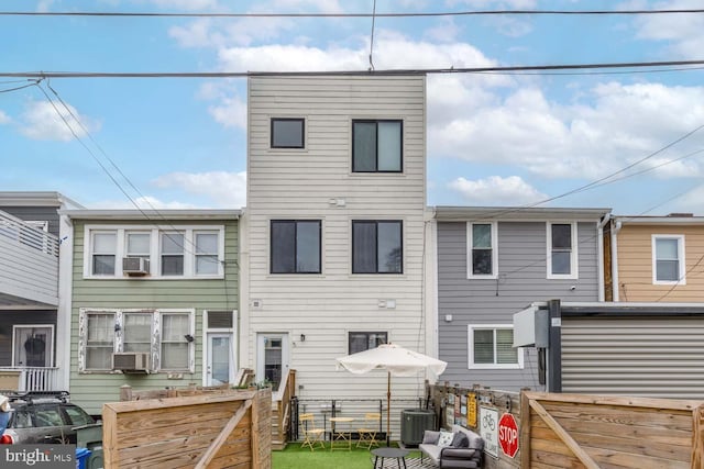 rear view of property featuring fence, cooling unit, and central air condition unit