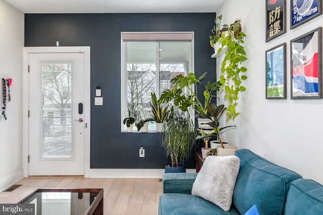 doorway to outside with a wealth of natural light, wood finished floors, and visible vents