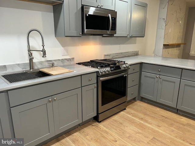 19 W 29th St, Wilmington, DE 19802 - kitchen with stainless steel appliances, gray cabinetry, a sink, light wood-style floors, and light countertops