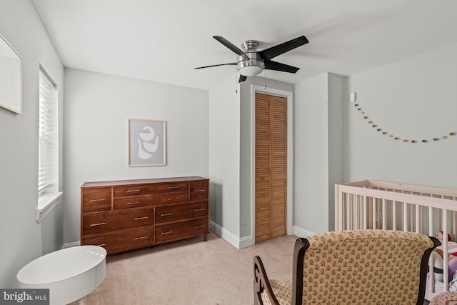 bedroom featuring baseboards, a ceiling fan, light colored carpet, and a closet