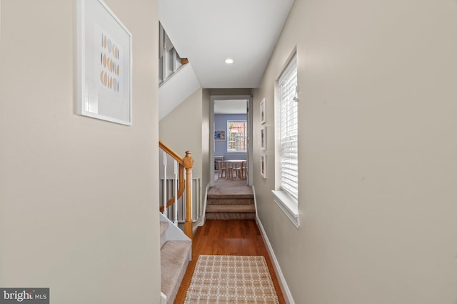 hall with wood finished floors, baseboards, recessed lighting, and stairs