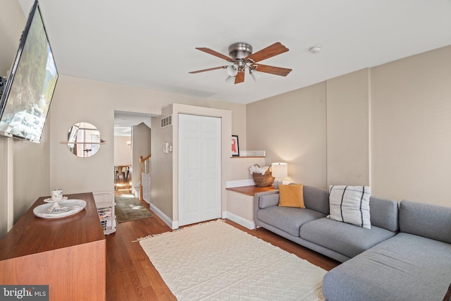 living room featuring wood finished floors, ceiling fan, visible vents, and baseboards