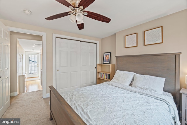 bedroom featuring light colored carpet, baseboards, a ceiling fan, and a closet