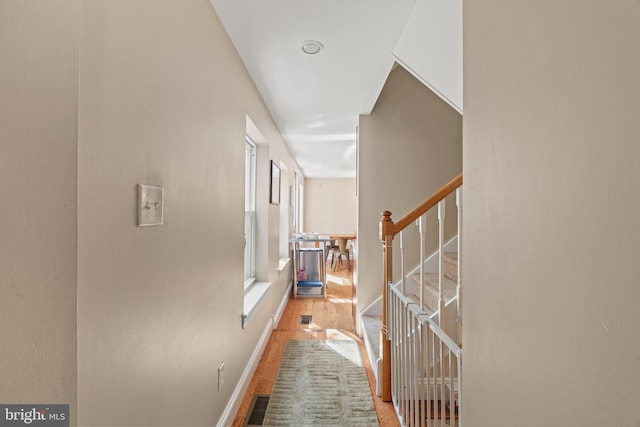 hallway with baseboards, visible vents, wood finished floors, and stairs