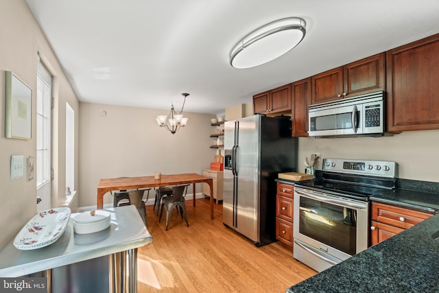 kitchen with a chandelier, decorative light fixtures, light wood-style flooring, dark countertops, and appliances with stainless steel finishes