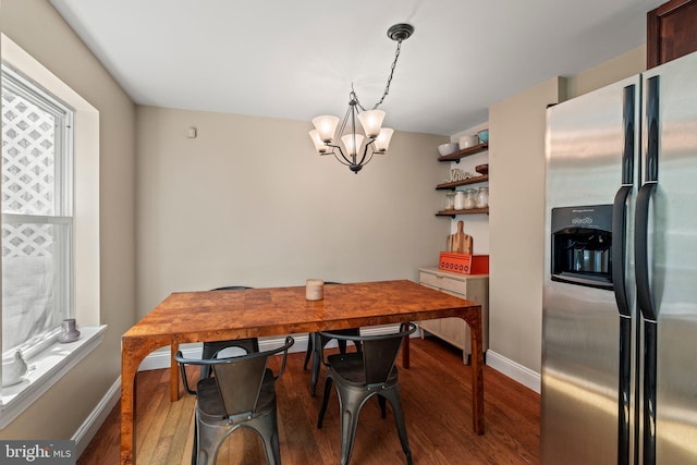dining area featuring baseboards, wood finished floors, and an inviting chandelier