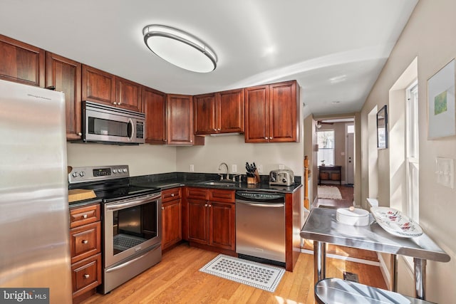 kitchen featuring stainless steel appliances, light wood-style flooring, and a sink