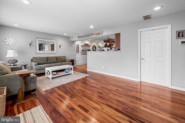 living room featuring baseboards, visible vents, wood finished floors, and recessed lighting