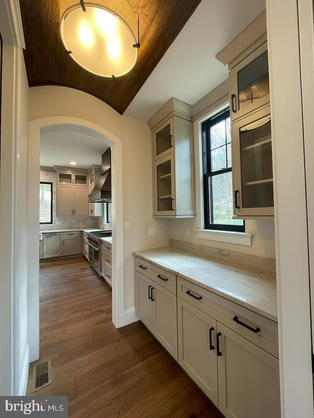 937 Swinehart, Boyertown, PA 19512 - kitchen featuring light stone countertops, dark wood-style flooring, glass insert cabinets, custom range hood, and arched walkways